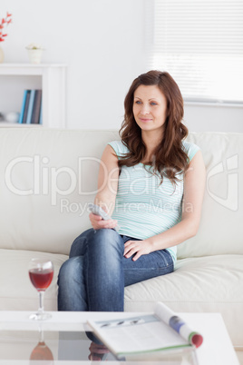 Woman sitting on a sofa while holding a remote control