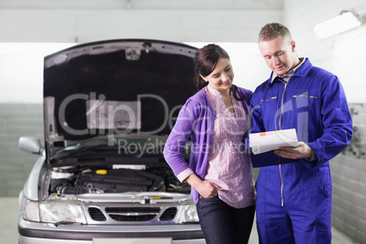 Mechanic showing a paper in a clipboard to a woman Mechanic showing a paper in a clipboard to a woman
