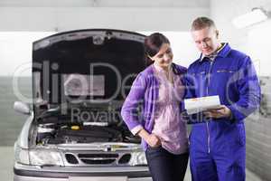 Mechanic showing a paper in a clipboard to a woman