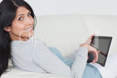 Woman touching a tablet screen while sitting on a couch