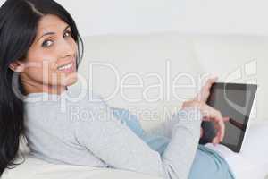 Woman touching a tablet screen while sitting on a couch