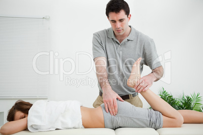 Woman lying while being stretched by a physiotherapist