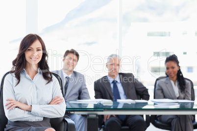 Smiling young businesswoman crossing her arms while accompanied