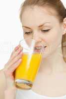 Woman drinking a glass of orange juice while looking at it
