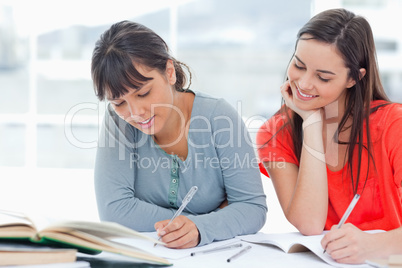 One girl looks over into the work of her friend