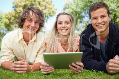 Three smiling students using a tactile tablet