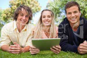Three smiling students using a tactile tablet