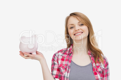 Woman holding a piggy bank while looking at camera