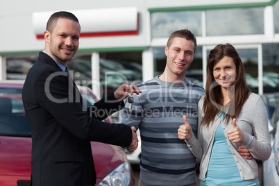 Dealer shaking hand of a man while giving him car keys