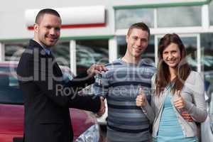 Dealer shaking hand of a man while giving him car keys