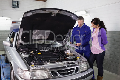 Mechanic showing a clipboard to a woman Mechanic showing a clipboard to a woman