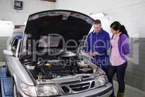 Mechanic showing a clipboard to a woman
