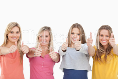 Four smiling girls giving the thumbs up