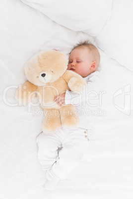 Baby sleeping while holding a teddy bear