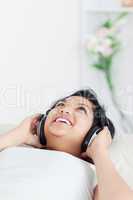 Smiling woman lying on a couch with headphones on