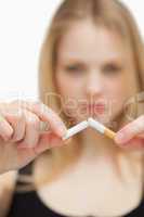 Close up of a blonde-haired woman breaking a cigarette