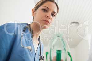 Nurse holding an oxygen mask while looking at camera