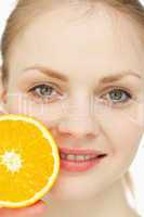 Close up of a woman placing an orange on her lips