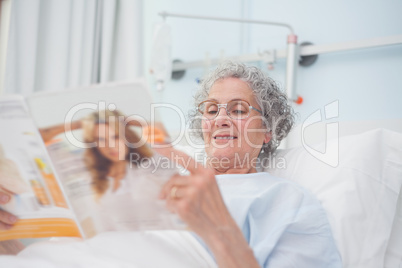 Elderly patient reading a magazine on her bed