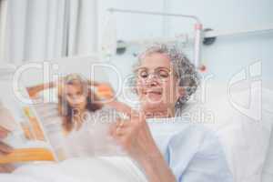 Elderly patient reading a magazine on her bed