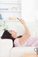 Woman laughing while resting on a couch and looking at a phone
