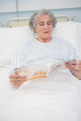 Patient reading a magazine on her bed