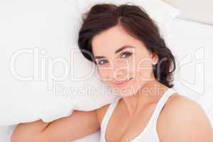 Brunette woman lying while placing her hand under a pillow