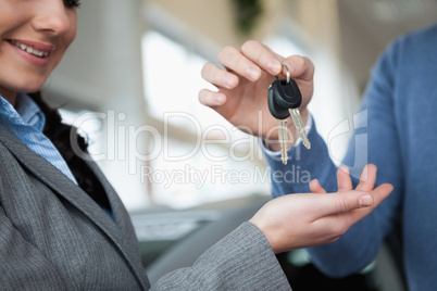 Smiling woman receiving keys from a hand