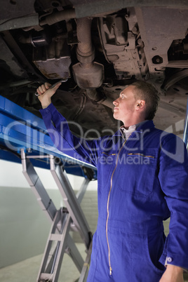 Mechanic repairing with a spanner the below of a car