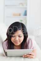 Woman lying on a sofa while looking at a tablet