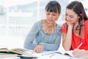 Two girls help one another as they study