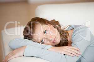 Woman crossing harms while lying on a sofa looking up