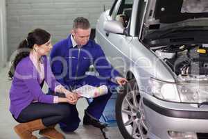 Mechanic showing the car wheel to a client