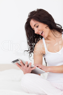 Cheerful woman holding her tablet pc while sitting