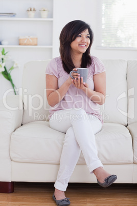 Woman sitting on a sofa while she is smiling