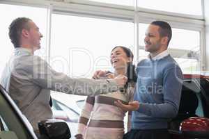 Laughing couple receiving keys from a salesman