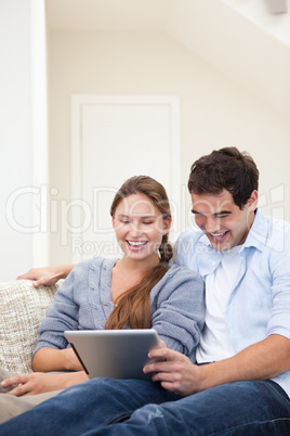 Couple laughing while holding a laptop