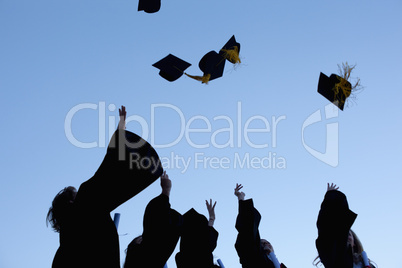 Five graduates throwing their hats in the sky