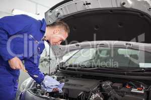 Mechanic looking at a dipstick while holding it