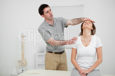 Serious practitioner placing his hand on the forehead of a woman