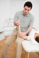 Serious physiotherapist holding the arm of a patient