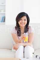 Smiling woman sitting and holding a glass of orange juice
