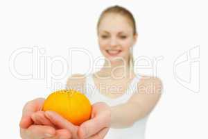 Cheerful woman presenting a tangerine