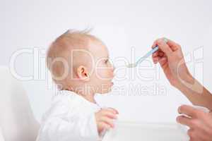 Cute baby sitting on a highchair while being fed