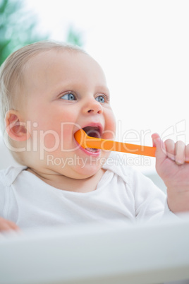 Baby holding a plastic spoon in his mouth