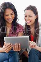 Close up half length shot of two laughing women looking at a tab
