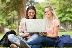 Happy teenagers sitting while using a laptop
