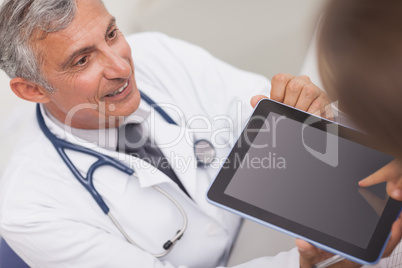 Doctor holding a tablet computer while looking at a patient