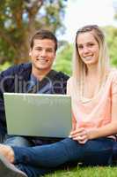Portrait of young people laughing while sitting with a laptop