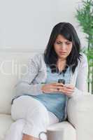 Woman using a phone while relaxing on a sofa